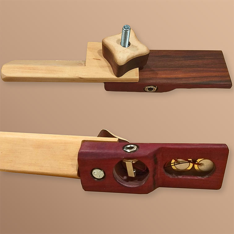 Picture of Desk Badger. The top part of the image shows the Desk Badger in playing position. The second image flips it over to show the bottom. The daxophone features a wood piece on the left that clamps to a table. On the right is a body with a quarter-inch jack and a flat top. The first piece acts as a clamp for the second and they are connected with a big wooden knob on a bolt. The bottom of the daxophone has a whole cut where the quarter-inch jack is embedded and a oval hole providing access to two piezo elements attached to the top plate.